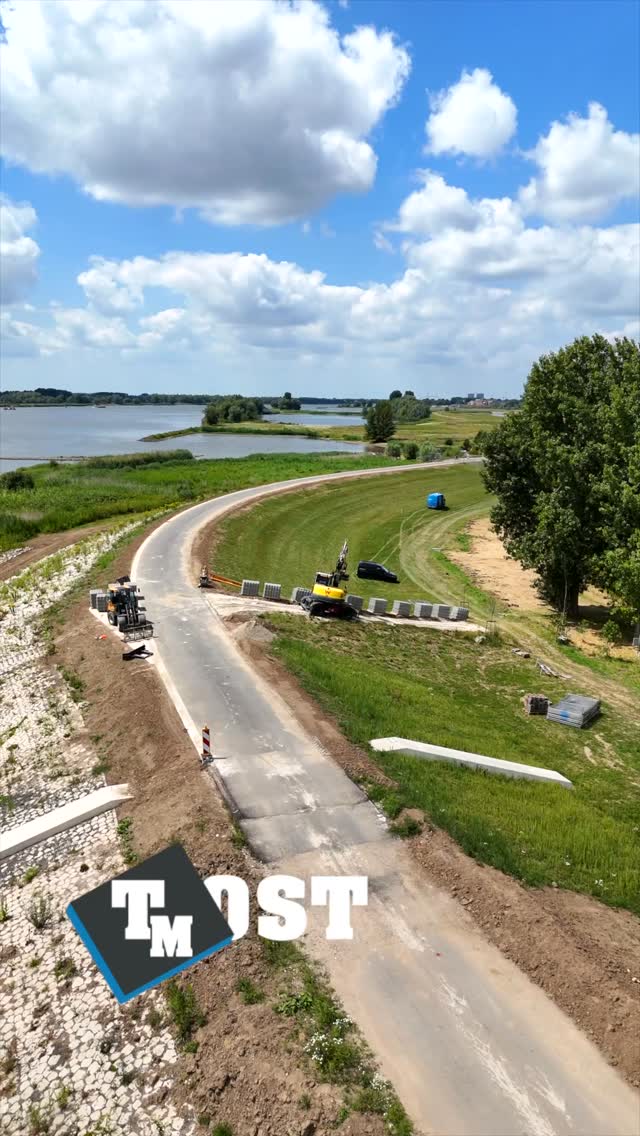 Dronebeeld van een rivierdijk waar machines bestrating leggen