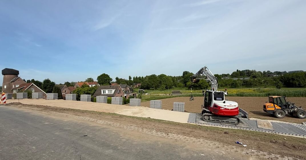 Werkzaamheden aan dijkverzwaring bij Gorinchem met steenkorven en graafmachine