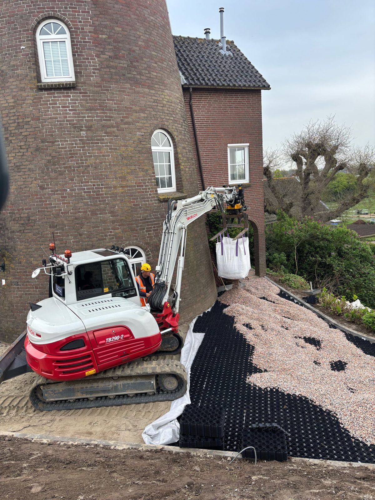 Rode graafmachine bij een woning langs het tracé