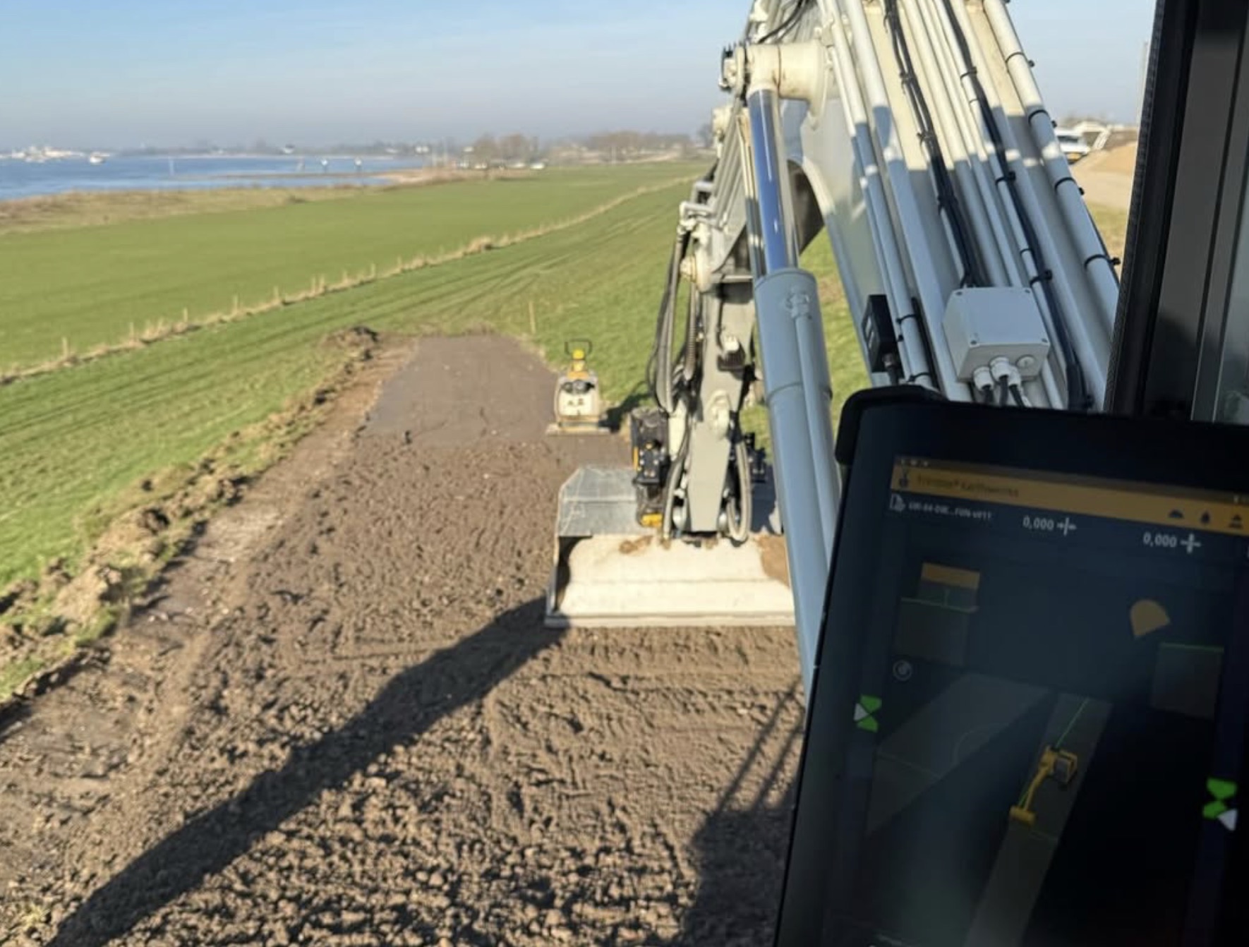GPS-bediening tijdens dijkwerk met zicht op uiterwaarden
