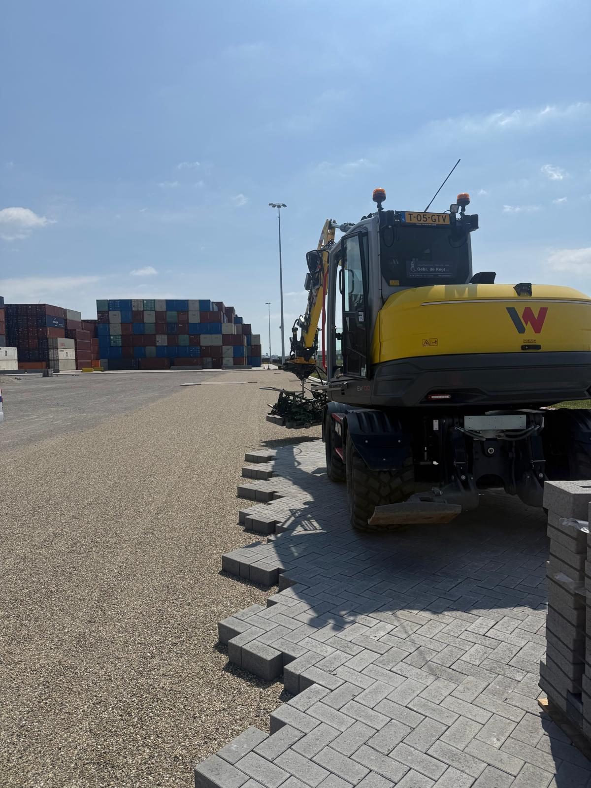 Gele graafmachine met machinist aan het werk op een terminal