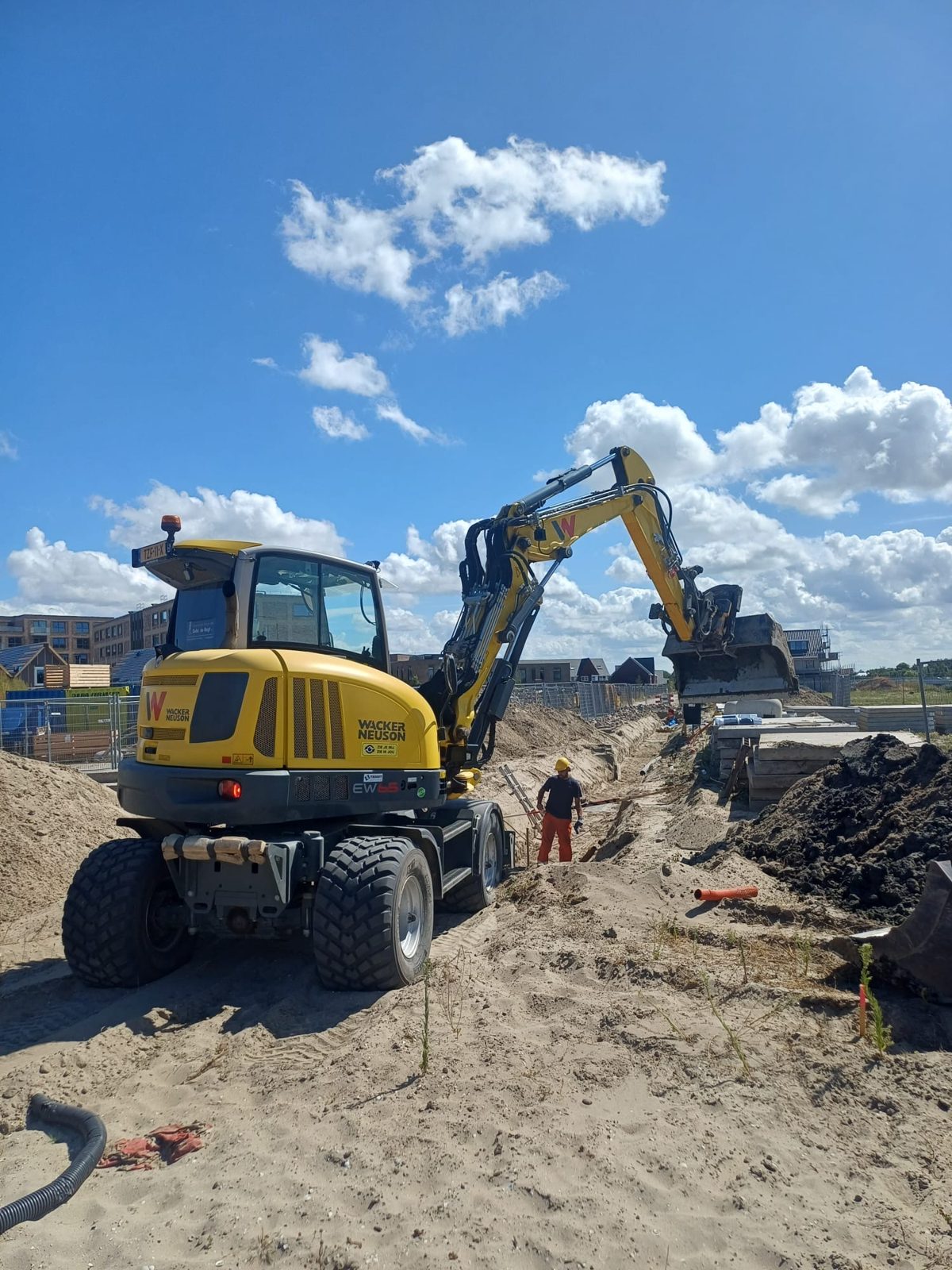 Grondwerk met de mobiele kraan, leidingwerk op de voorgrond