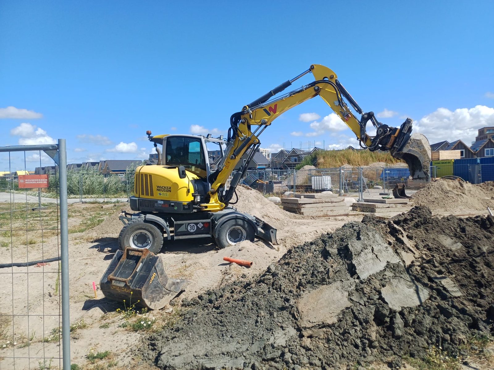 Mobiele kraan aan het werk langs de bouwhekken