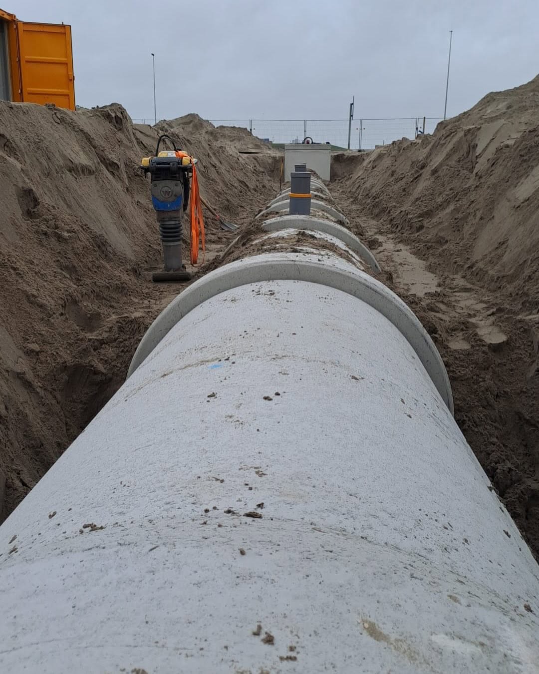 Aanleg van een grote rioolbuis in een uitgegraven sleuf op de Maasvlakte