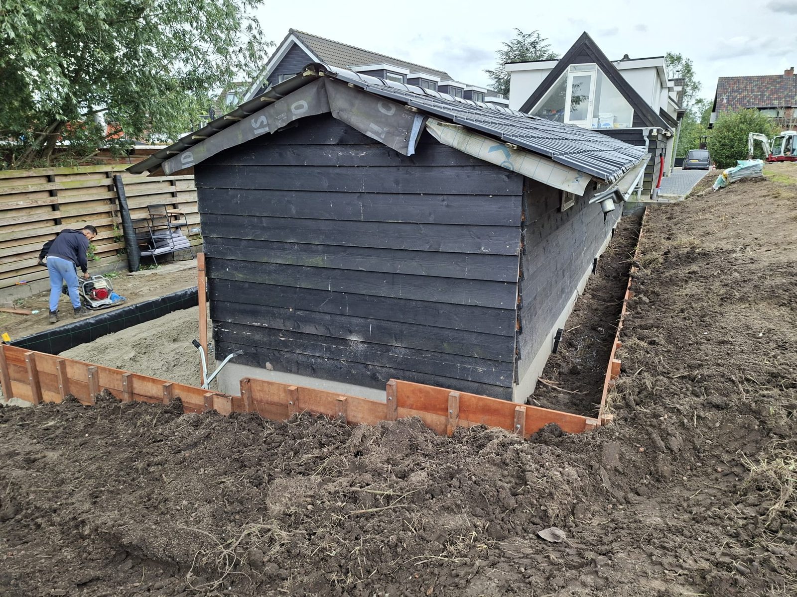 Bestrating met houten opsluiting rondom het bijgebouw